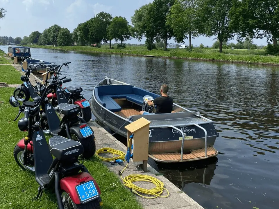 E-choppers naast een sloep aan de vaart in Giethoorn