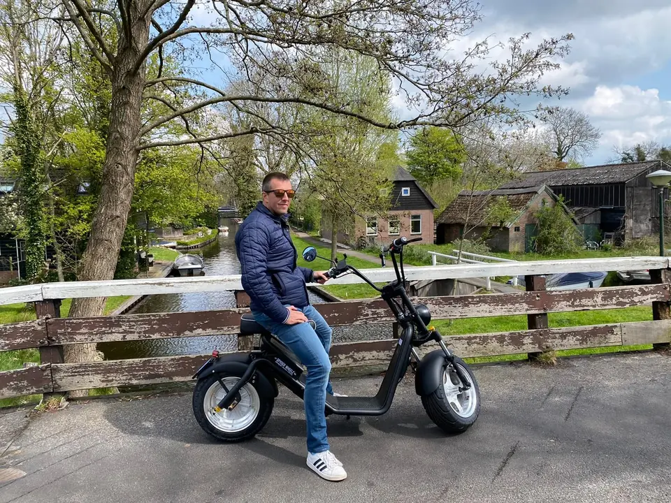 Man op een e-chopper bij een houten hek aan het water in Giethoorn